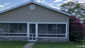 A single-story house with a gabled roof, a front porch with a glass enclosure, and a stone foundation. - Visit our charming cottage this Fall & Winter. Enjoy the Scenery & Ski Slopes. (McKnightstown)