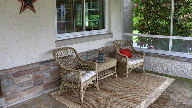 A cozy patio with wicker furniture, a star decoration, and a view of a garden through large windows. - Visit our charming cottage this Fall & Winter. Enjoy the Scenery & Ski Slopes. (McKnightstown)