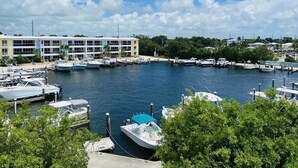 A marina with boats docked, a large building with multiple floors, and a clear blue sky with clouds. - PARADISE FOUND! (Key Largo, FL 33037)