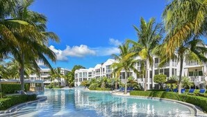 A resort pool with palm trees, lounge chairs, and a building with balconies. - PARADISE FOUND! (Key Largo, FL 33037)