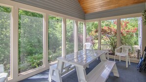A covered patio with a wooden ceiling, large windows, and a picnic table with chairs. - Picturesque Ski getaway close to Loon Mountain and Waterville Valley Ski Resorts (Thornton)