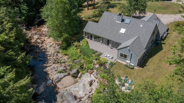 A modern house with a large deck, a river nearby, and a well-maintained garden. - Picturesque Ski getaway close to Loon Mountain and Waterville Valley Ski Resorts (Thornton)
