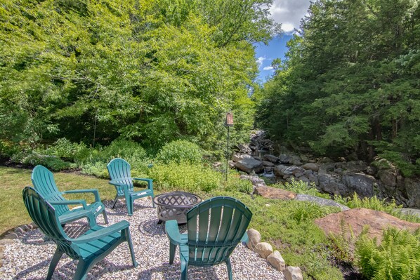 Relax in a serene outdoor setting surrounded by trees and a gentle stream.