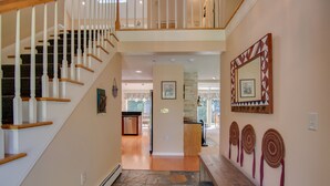 A staircase with wooden steps and white balusters leading to a second floor. A hallway with a stone floor and a wooden bench runs parallel to the stairs. - Picturesque Ski getaway close to Loon Mountain and Waterville Valley Ski Resorts (Thornton)