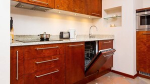 Una cocina compacta con armarios de madera, lavavajillas integrado y horno de acero inoxidable.