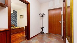 Un pasillo con una puerta de madera, un perchero y una cama con papel tapiz floral.