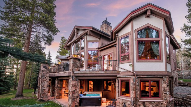 Une maison en pierre à plusieurs étages, dotée d’une cheminée en pierre, d’un espace salon extérieur et d’un jacuzzi.