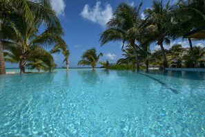 Une piscine d’un bleu éclatant, entourée de palmiers, sous un ciel dégagé.