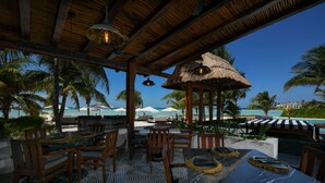 An outdoor dining area with wooden furniture, a patterned floor, and a view of the ocean. - Casa del Jaguar Beach Hotel (Isla Mujeres)