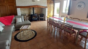 A cozy living room with a fireplace, a dining table with chairs, and a sofa.