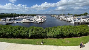 A marina with numerous boats docked, a clear sky, and a grassy area in the foreground. - Burnt Store Isles Golf Home, W/Hot Tub/King Bed/Fast WIFI/Unbeatable Location (Punta Gorda)
