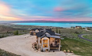 Une grande maison moderne, dotée d’une allée spacieuse et offrant une vue sur un lac.
