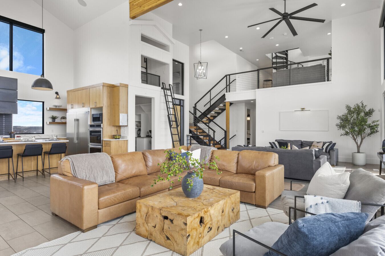 Un vaste espace de vie comprenant un canapé en cuir, une table basse et un escalier menant à un niveau supérieur.