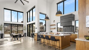 Een moderne keuken met een groot eiland, barkrukken en een eethoek met een tafel en stoelen.