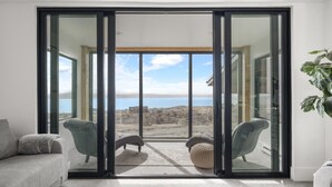 Een moderne woonkamer met een schuifdeur die leidt naar een balkon met uitzicht op zee.
