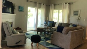 Una sala de estar con sofá, sillón, otomanas y chimenea.