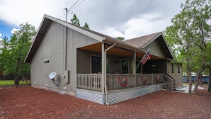 Ein Holzhaus mit Veranda, Satellitenschüssel und amerikanischer Flagge.