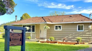 Une maison à deux étages avec un toit brun, une véranda dotée d’une balustrade et une enseigne sur laquelle on peut lire : « Bienvenue chez Brownings Vacation Rentals ».
