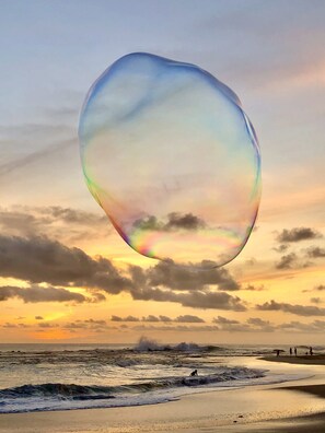 Una spiaggia con una grande bolla a forma di cuore che fluttua sull'acqua.