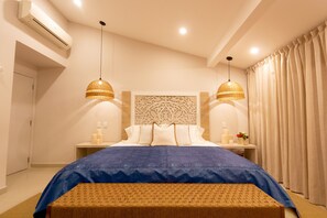 Un dormitorio con cama, dos mesitas de noche, un cabecero decorativo y un ventanal con cortinas.