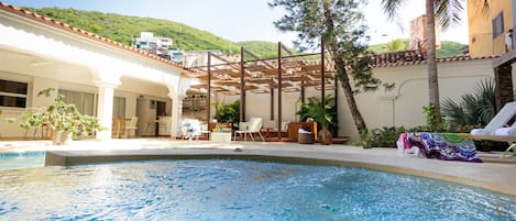 Una piscina al aire libre, sillones reclinables de piscina