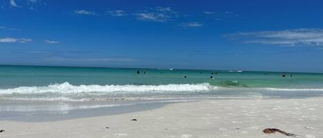 A beach with clear blue water and a sandy shore.