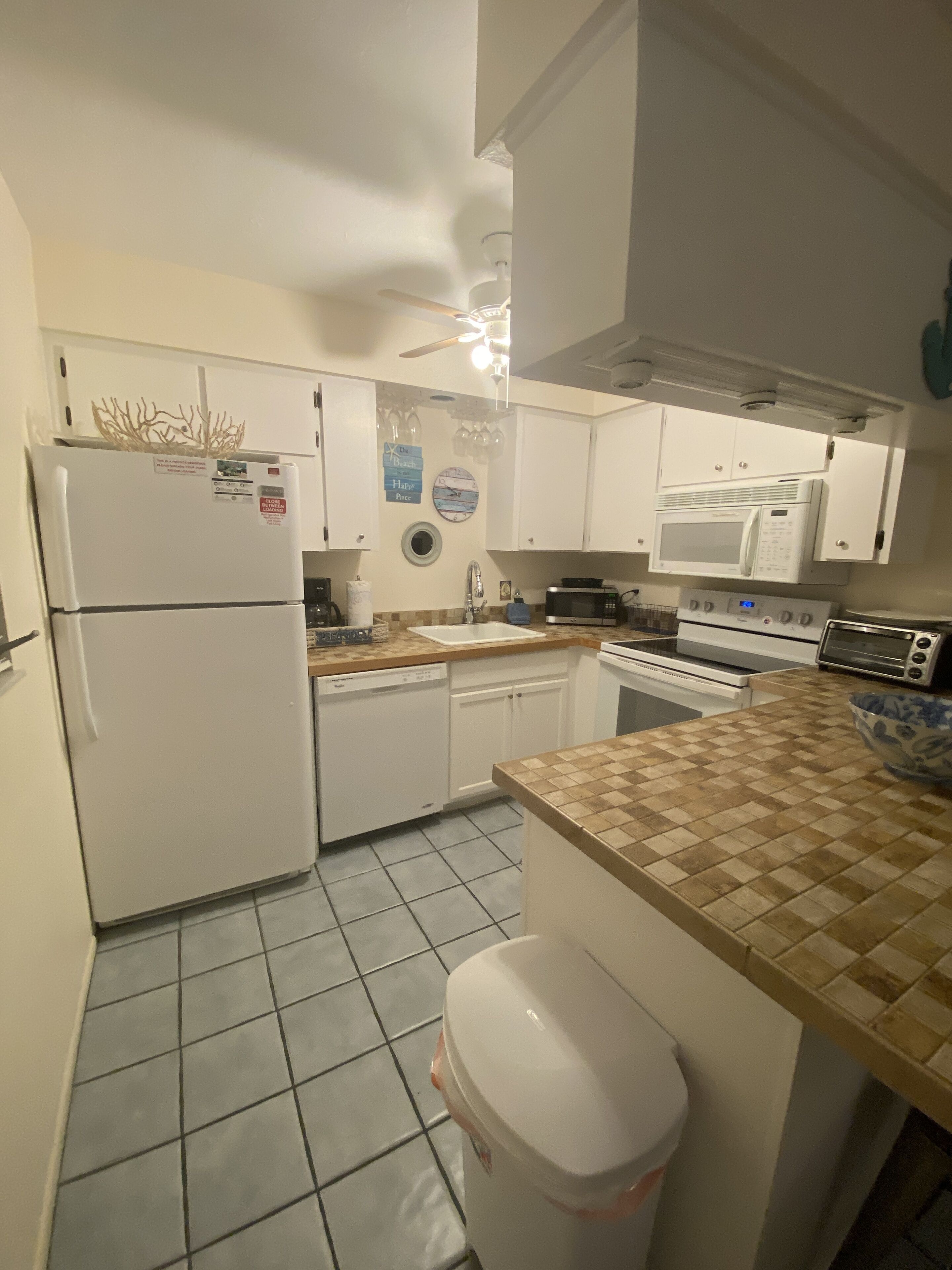 A compact kitchen with white cabinets, a refrigerator, a microwave, a stove, and a dishwasher.