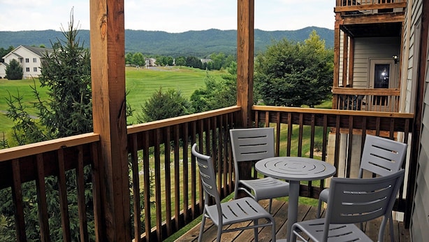 A balcony with a wooden railing, two grey chairs, and a small round table. - 2 bdr, 2 baths, golf, spa, water park for FAMILY FUN in Virginia (Massanutten)
