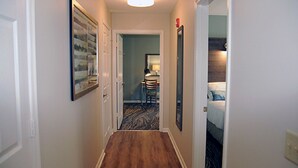 A narrow hallway with a wooden floor leading to a room with a bed and a chair. - 2 bdr, 2 baths, golf, spa, water park for FAMILY FUN in Virginia (Massanutten)