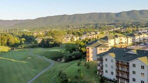 A golf course with a path leading to a building with multiple floors and balconies. - 2 bdr, 2 baths, golf, spa, water park for FAMILY FUN in Virginia (Massanutten)