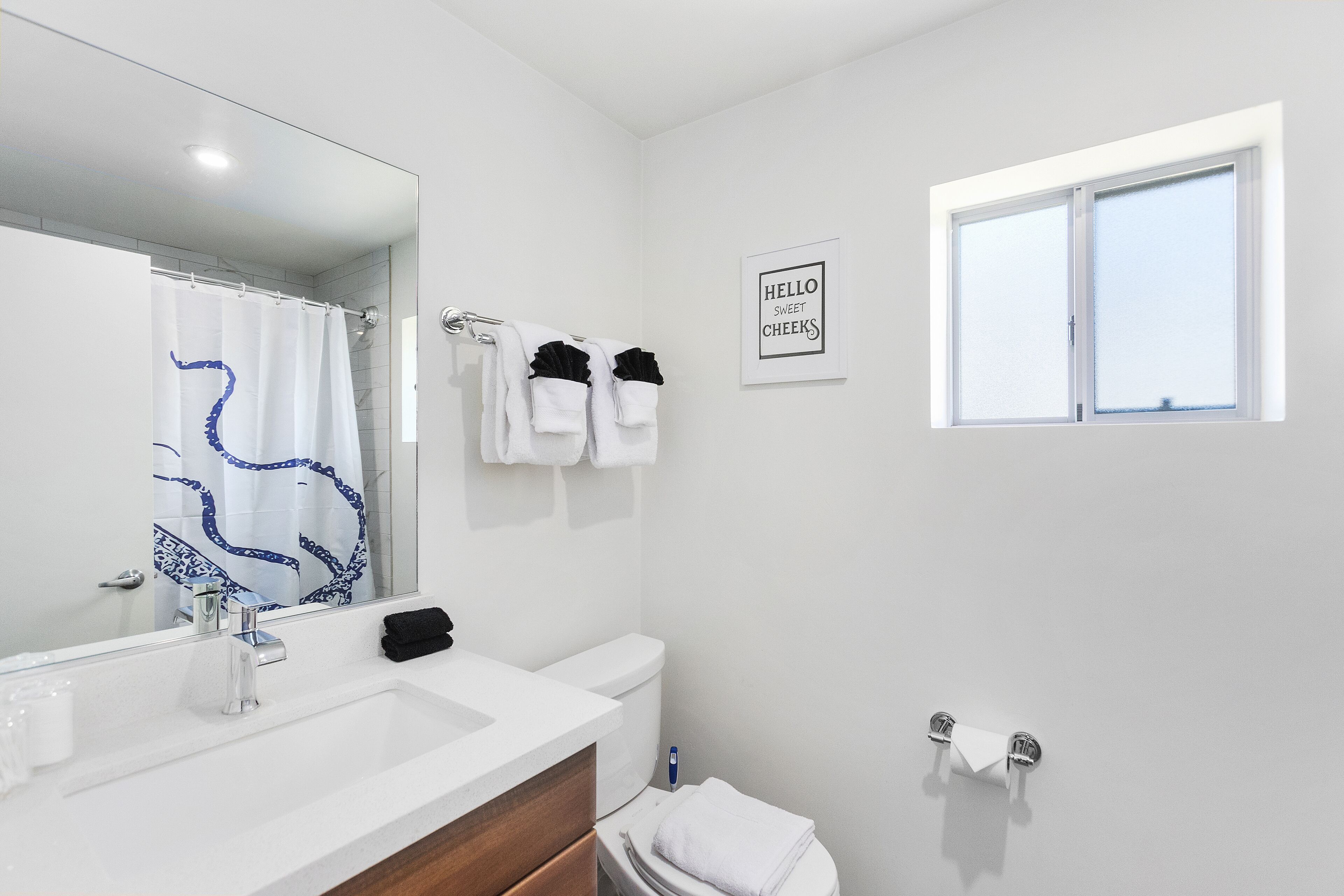 Un baño con un lavabo blanco, un espejo, un inodoro y una ventana.