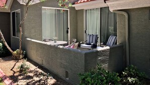 A residential building with a patio area, a sliding glass door, and a small table with chairs.