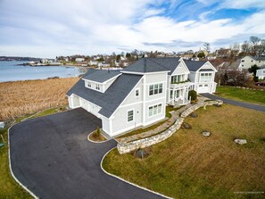 A large, two-story house with a stone foundation and a curved driveway leading to a gated entrance.