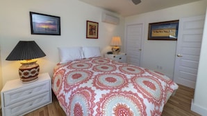 Una camera da letto con un letto, un comodino con una lampada, due quadri appesi al muro e una ventola a soffitto.