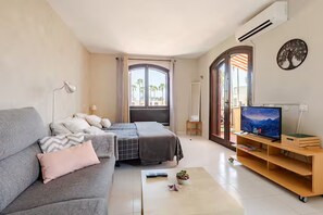 A modern living room with a sofa, a bed, a TV, and a small table with a plant. - Spacious, bright studio with a terrace and a view of the pool (Arona)