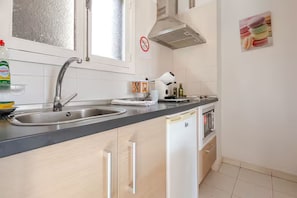 A kitchen with a stainless steel sink, a white refrigerator, and a microwave.