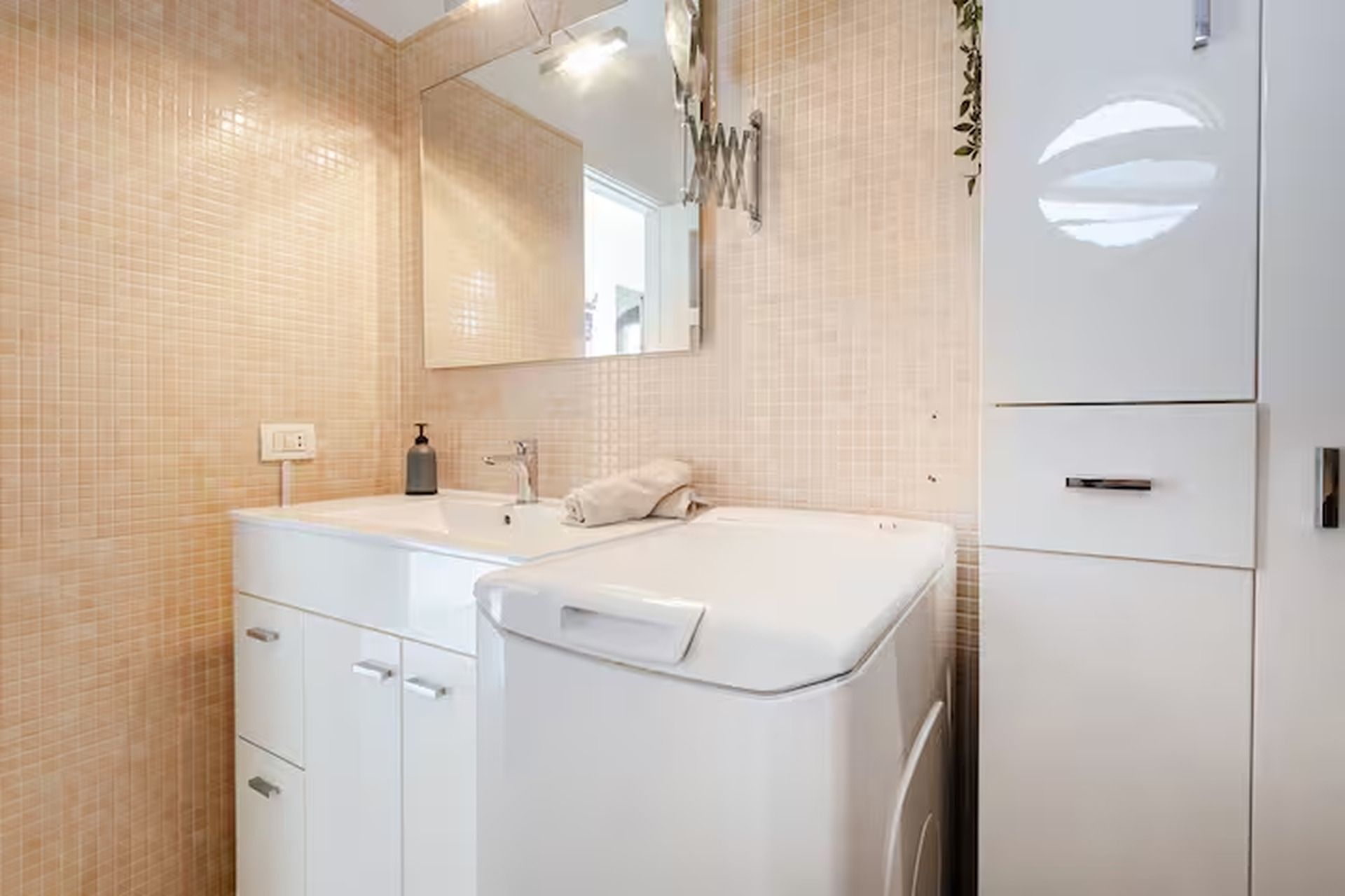 A bathroom with a white sink, mirror, and cabinet.