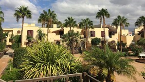 A resort with multiple buildings, palm trees, and a clear sky.