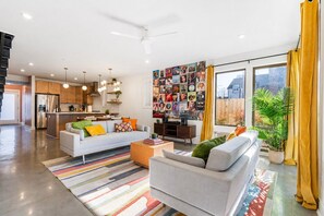 A modern living room with a sofa, coffee table, and a wall adorned with photographs. - Group-friendly home one mile from Nissan Stadium (Nashville)