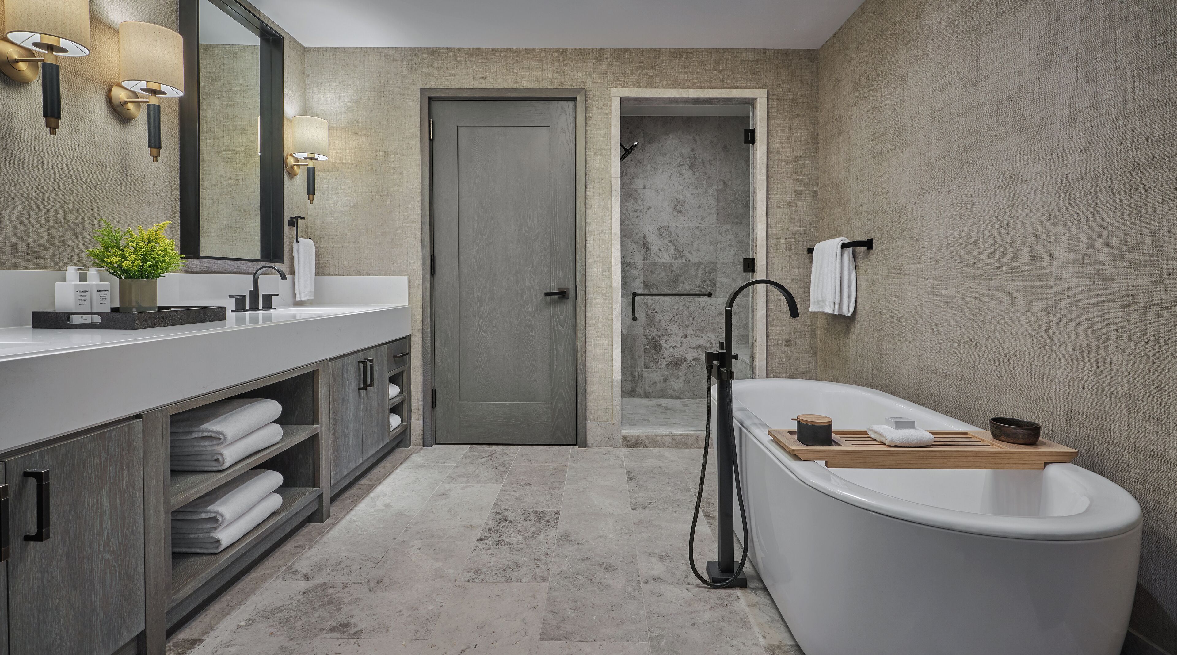 A modern bathroom with a freestanding bathtub, a large mirror, and a vanity with a sink and towel rack.
