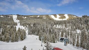 Une piste de ski enneigée, avec un télésiège et un bâtiment au toit rouge.