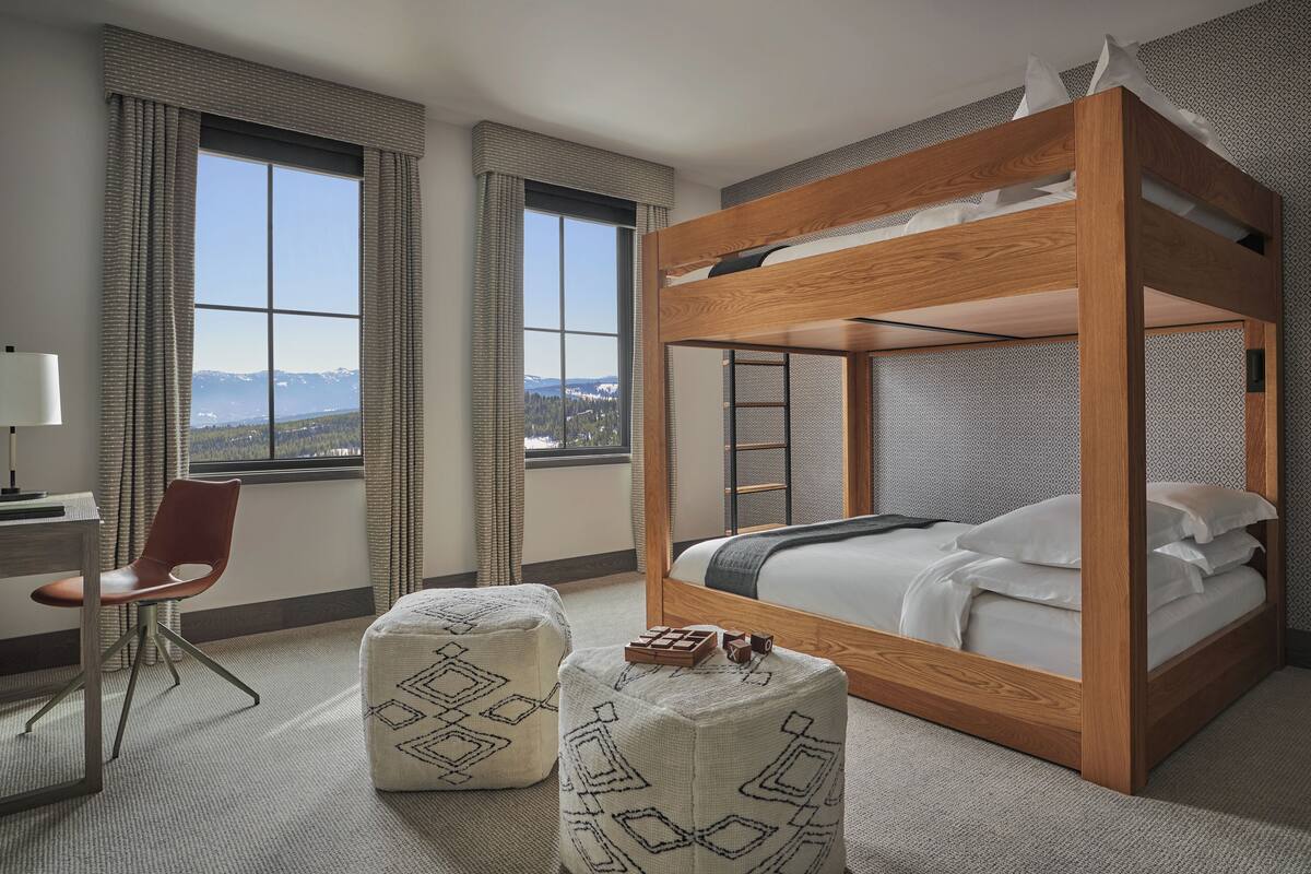 Ein Zimmer mit Etagenbett, Schreibtisch und Stuhl sowie Bergblick durch große Fenster.