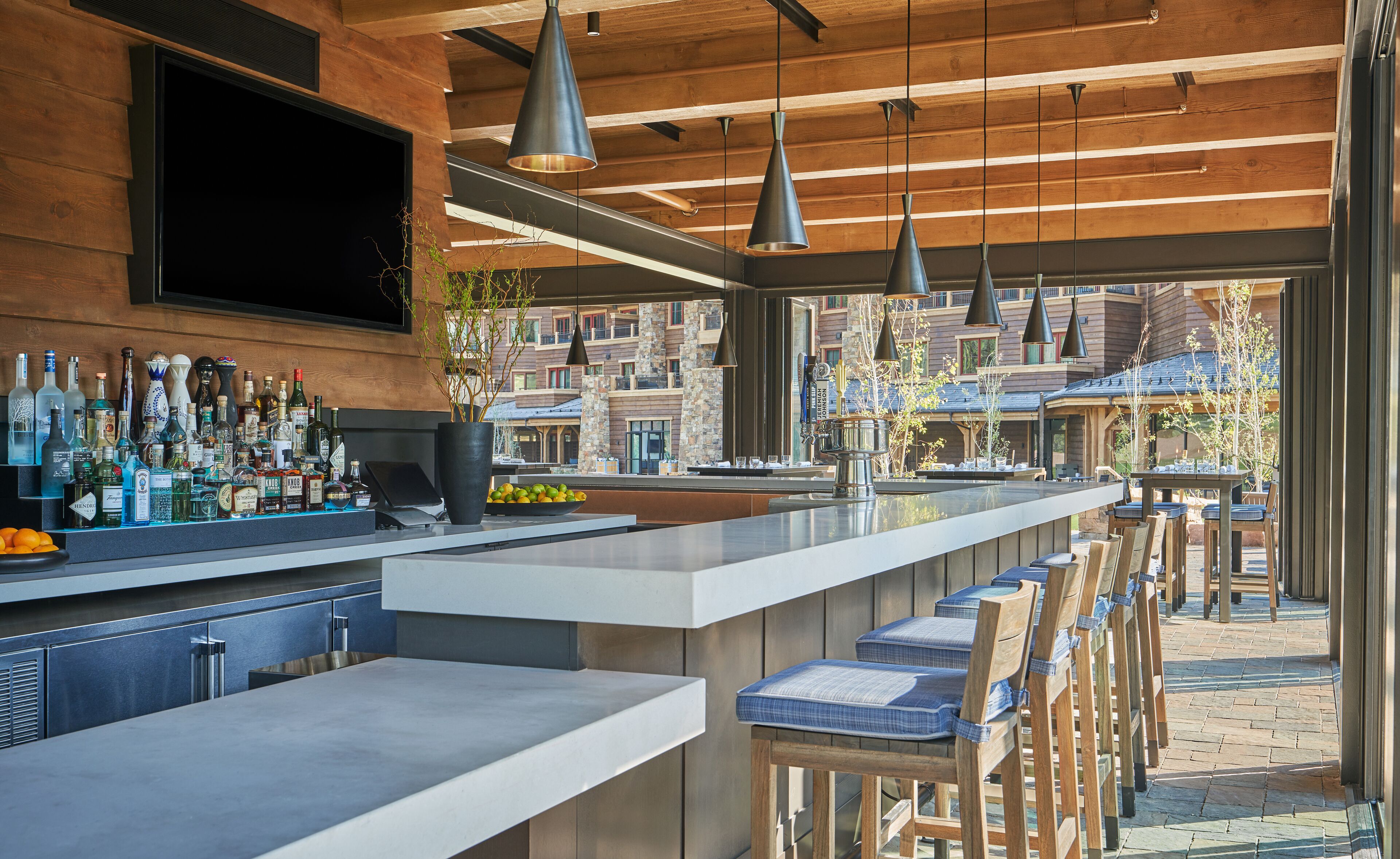 A modern bar area with a long counter, multiple seating options, and a view of the surrounding buildings.