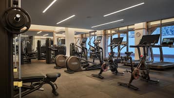 Une salle de sport équipée de machines de cardio, d’appareils de musculation et de grandes fenêtres donnant sur l’extérieur.