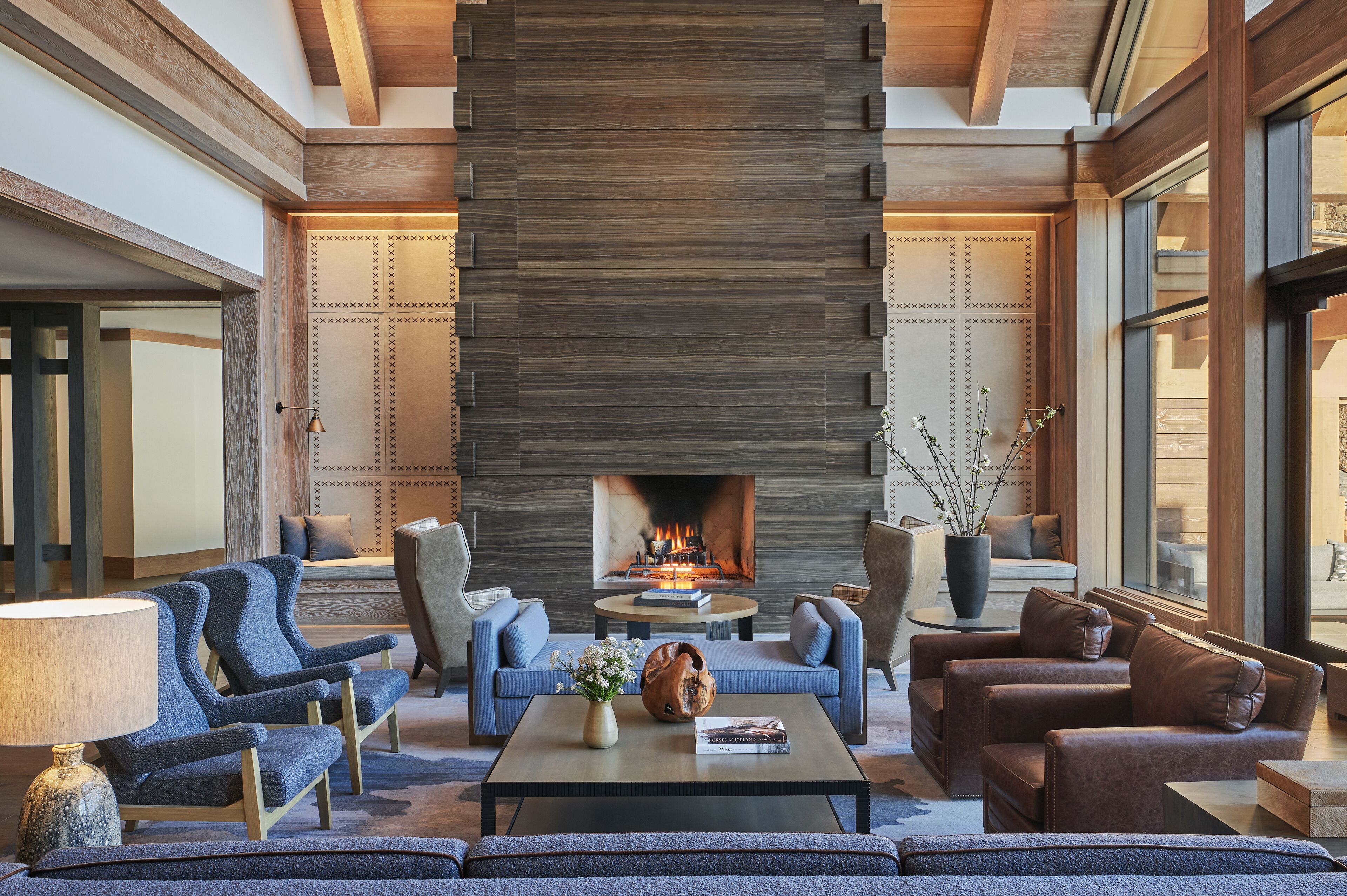 A spacious lobby with a large fireplace, comfortable seating, and a view through large windows.