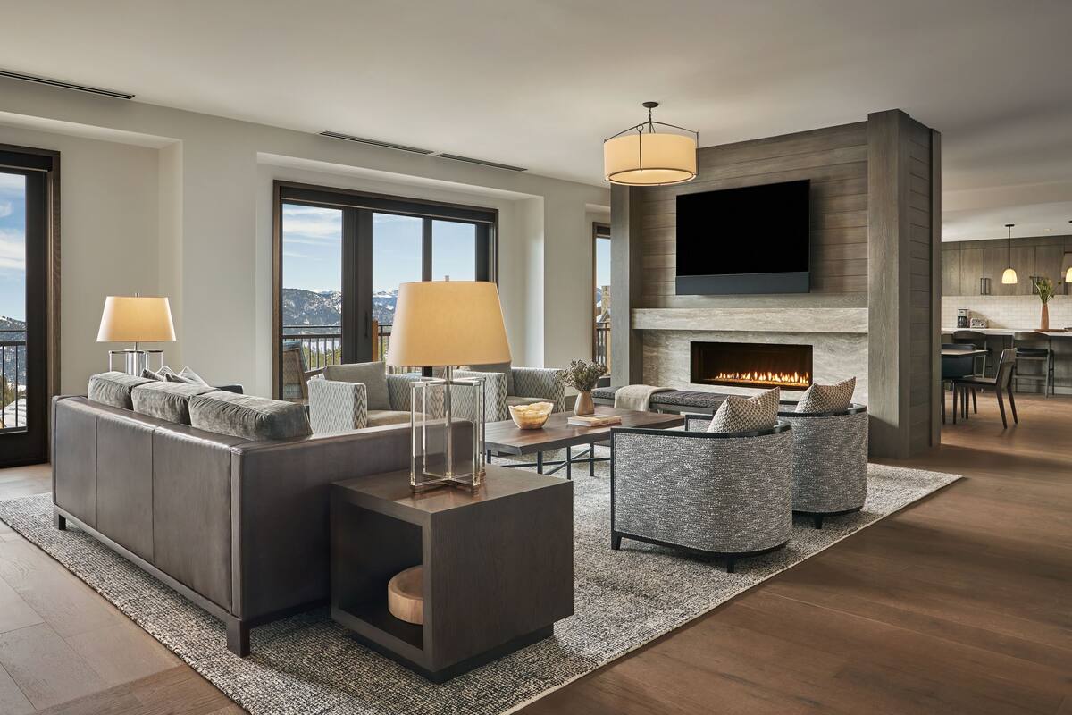 Ein modernes Wohnzimmer mit Kamin, großem Fernseher und Blick auf die Stadt.