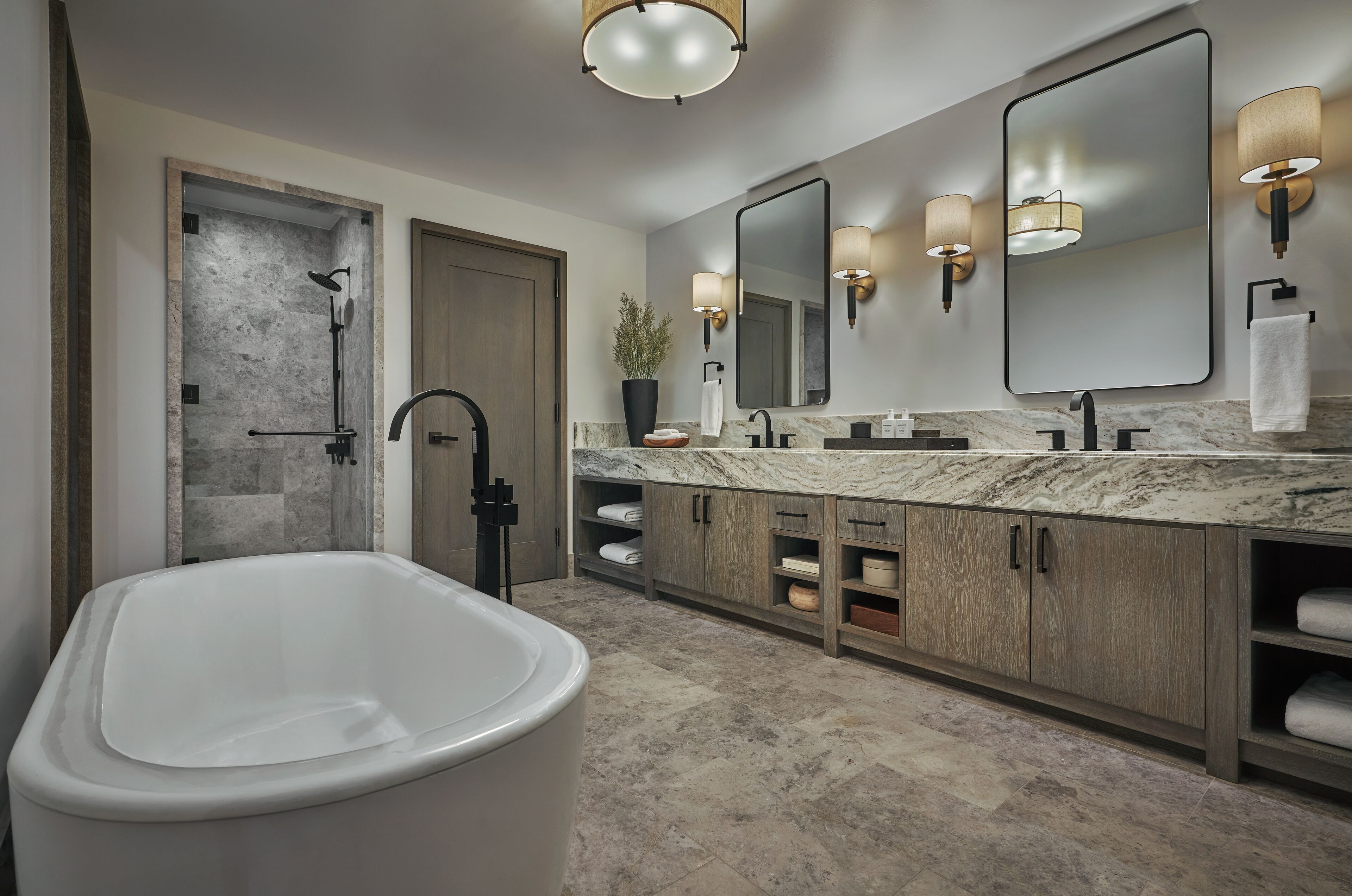 A modern bathroom with a freestanding bathtub, a walk-in shower, and a large mirror with wall sconces.