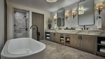 A modern bathroom with a freestanding bathtub, a walk-in shower, and a large mirror with wall sconces.