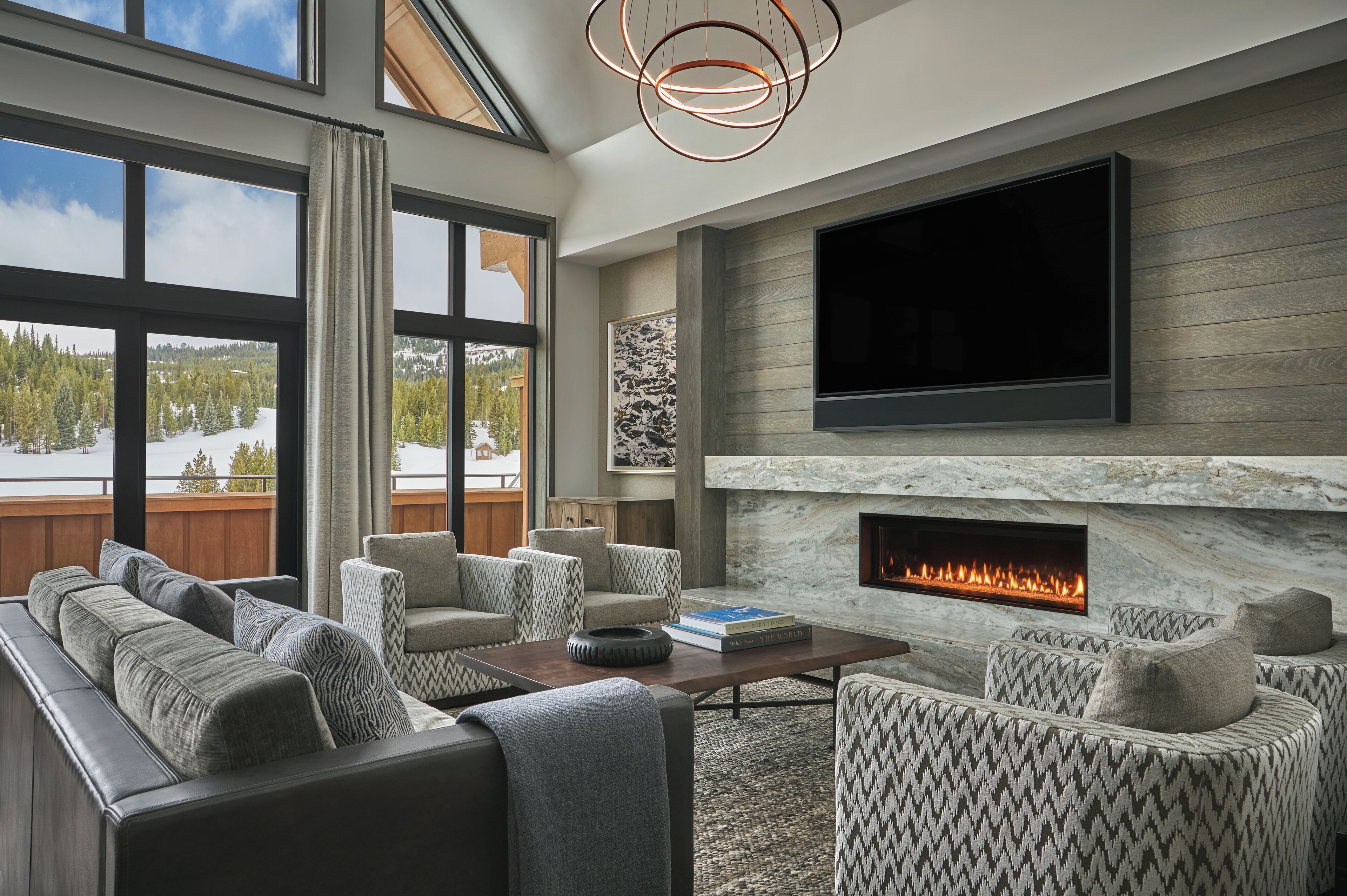 A modern living room with a fireplace, large windows, and a flat-screen TV.