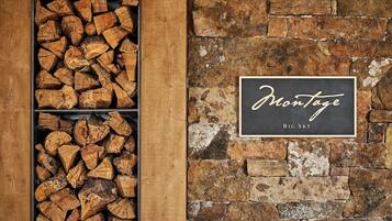 A fireplace with stacked firewood and a sign that reads "Montage Big Sky".